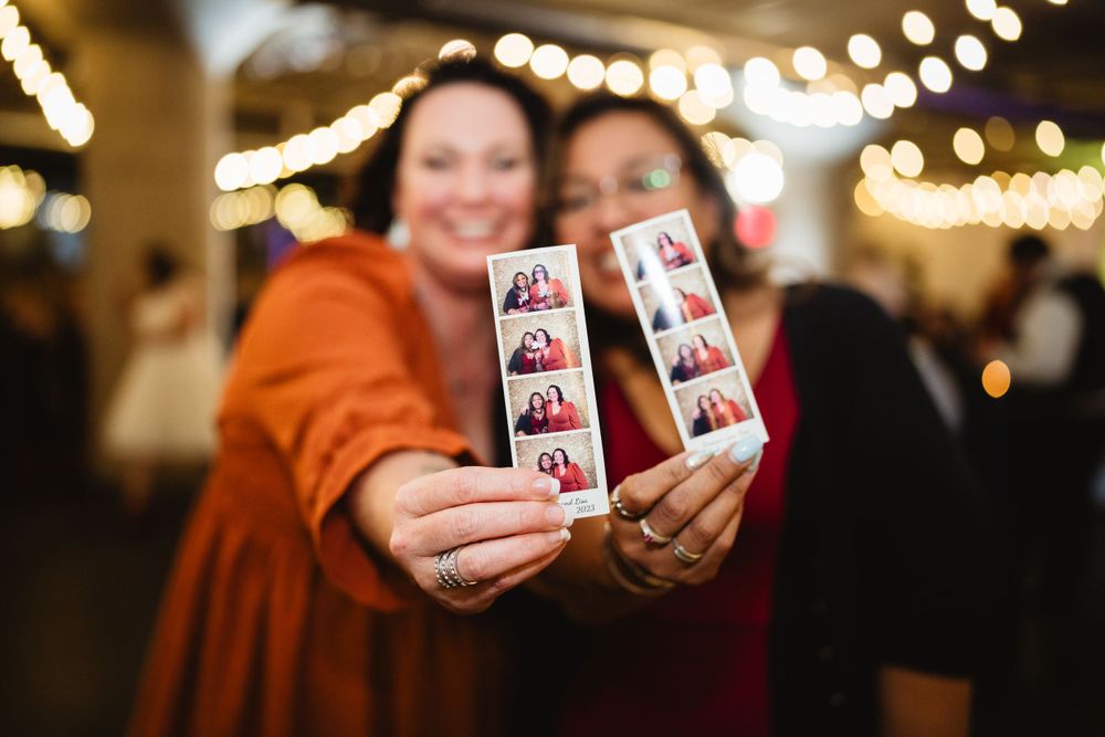 Hands holding photo booth strips displaying memorable moments from the celebration.