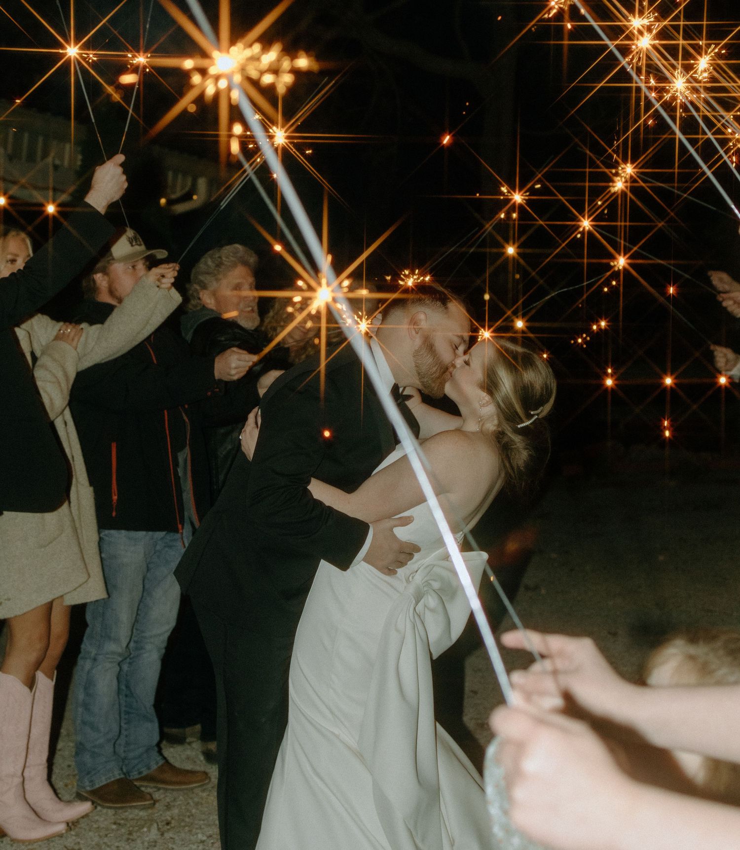 Wedding celebration with sparklers creating magical star-like effects in the night sky.