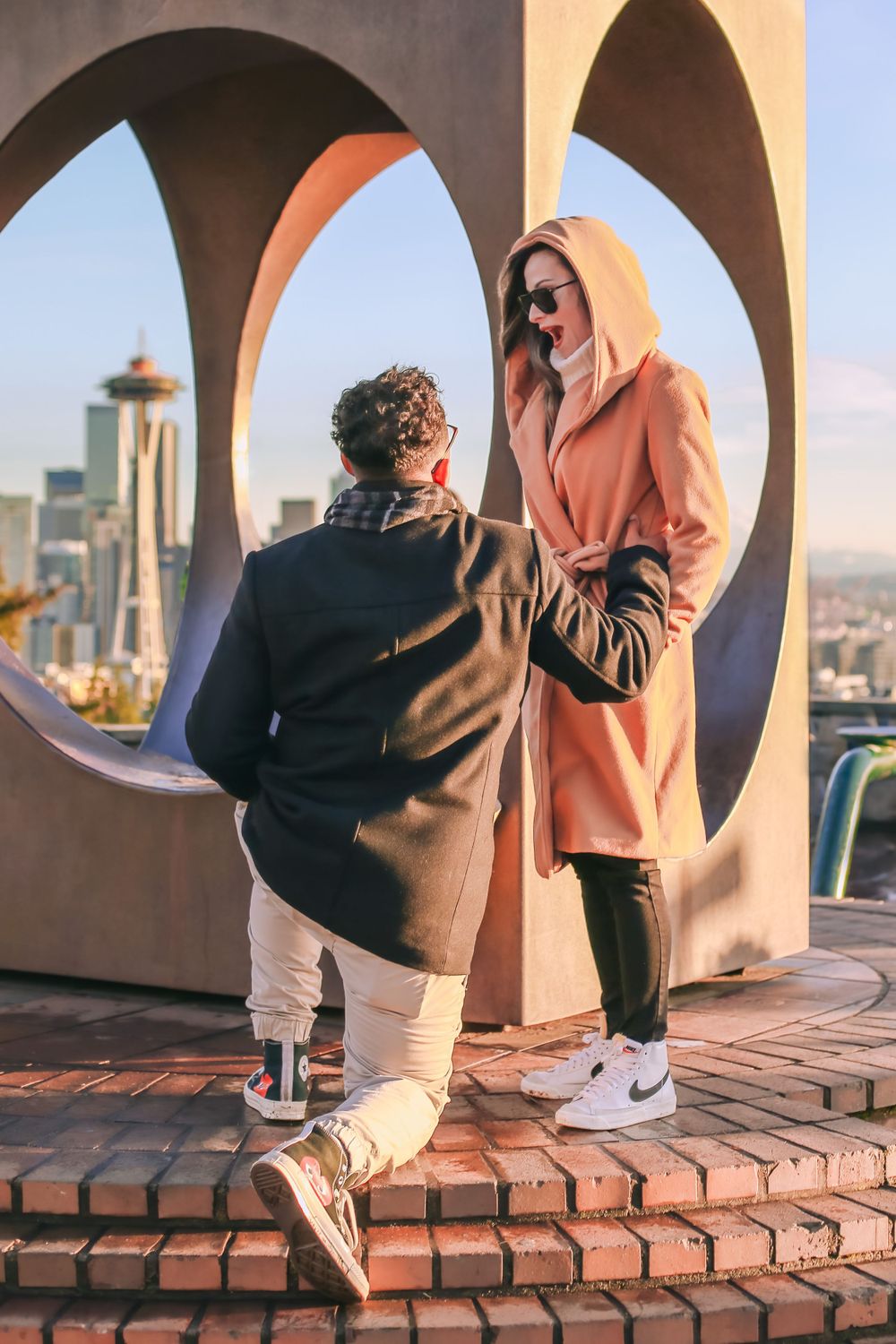 A proposal moment captured through architectural arches with the Seattle skyline in view. Spokane Liberty Lake Photographer Family
