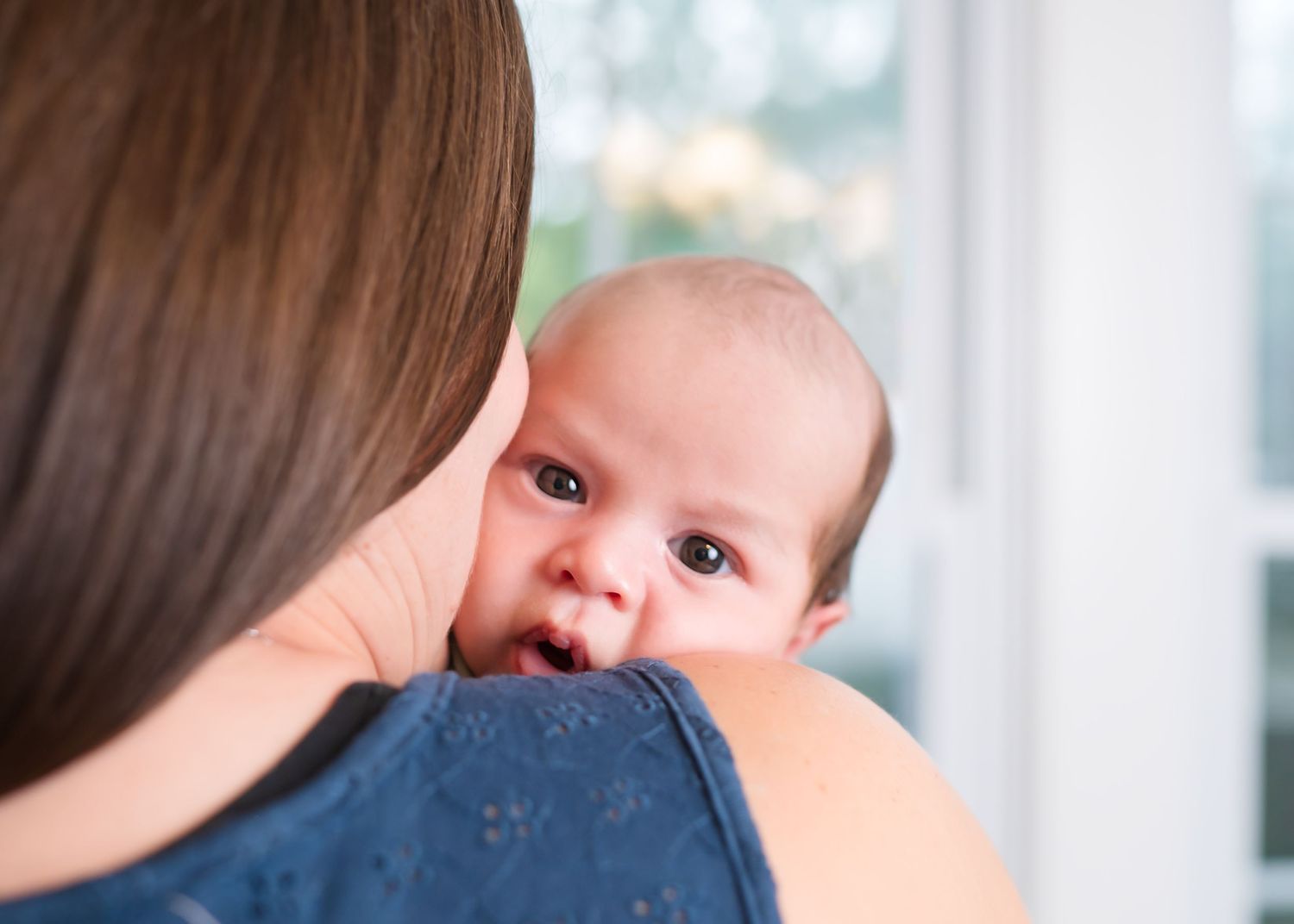 A tender moment between parent and baby against a bright window. Northern Virginia & DMV photographer