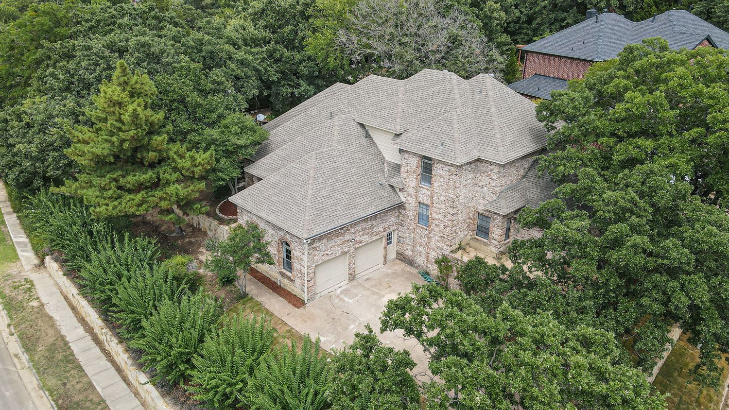drone footage of large two story home on top of hill surround by trees