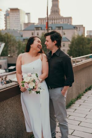 A couple shares a joyful moment on a city rooftop with historic architecture in the background.