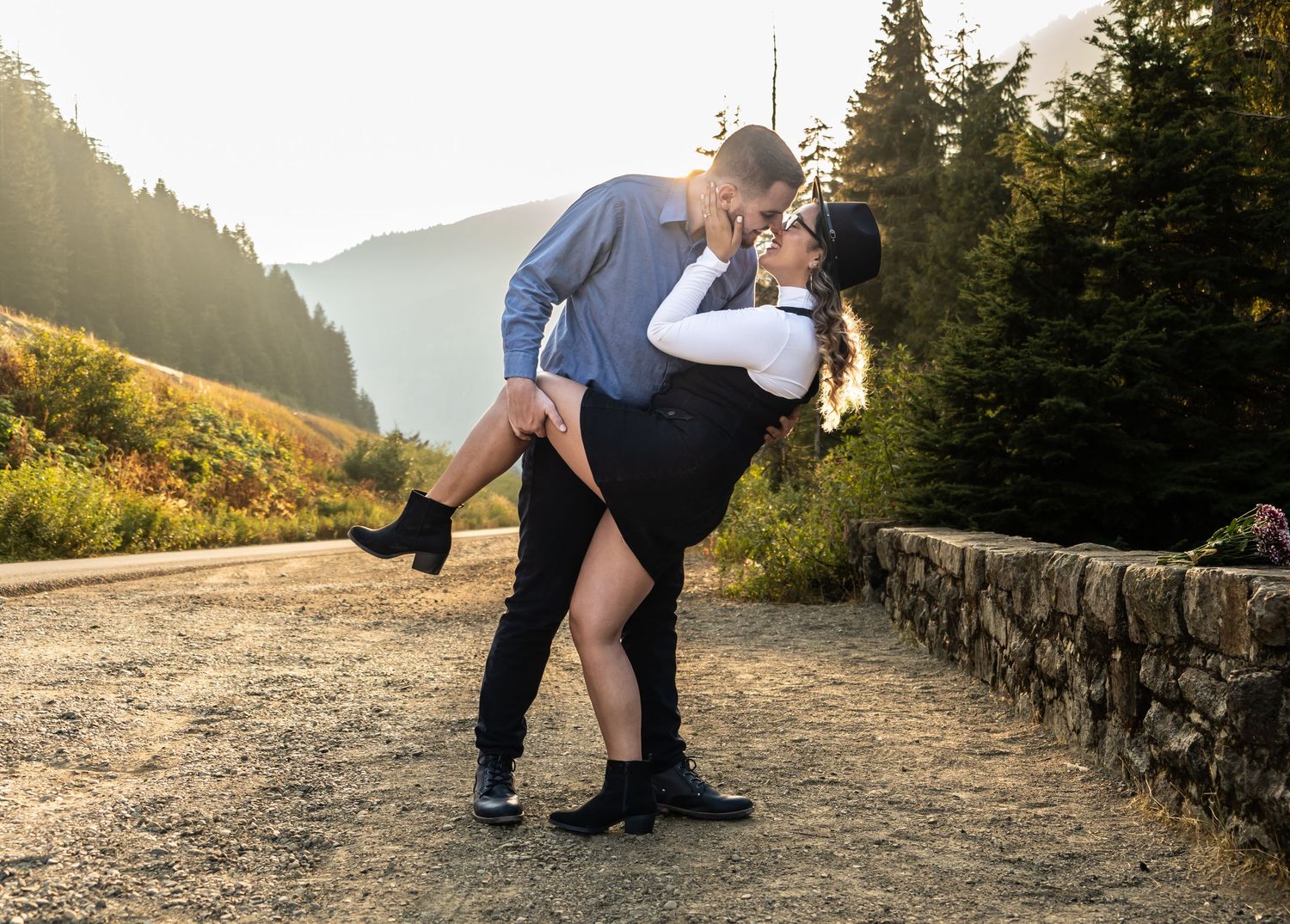 Dancing couple in romantic dip pose on mountain trail during sunset.