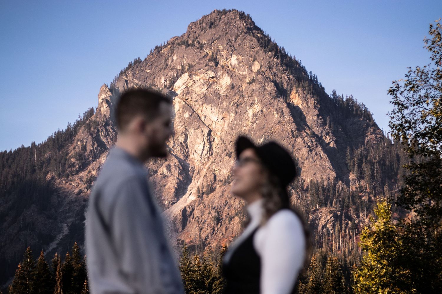 Couple silhouetted against dramatic mountain peak during engagement photoshoot.