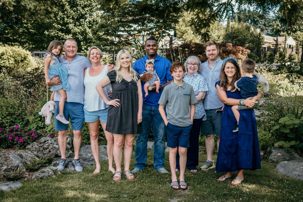 A large family smiles in a wide group shot, showcasing three generations