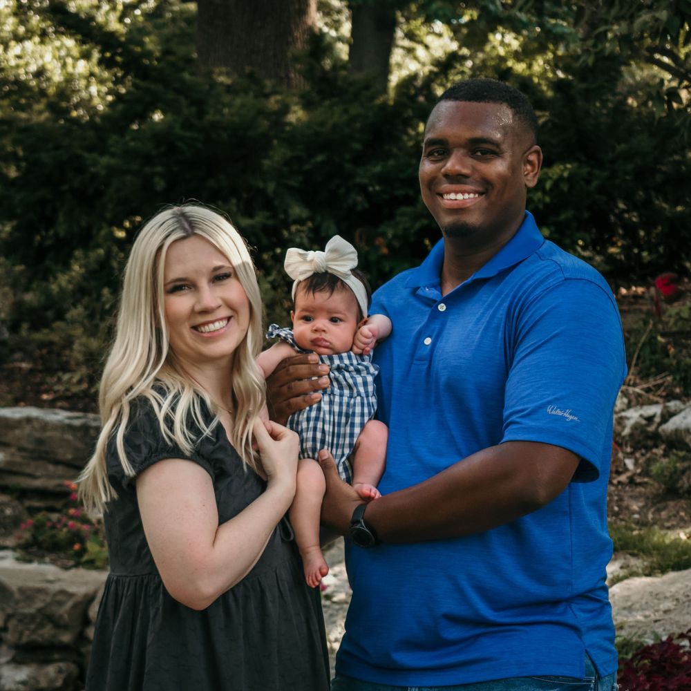 A lovely couple smiles wide as they pose with their newborn
