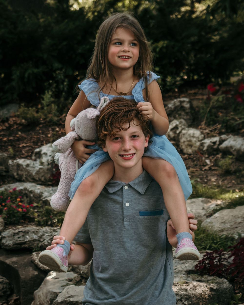 A young boy gives his little sister a piggyback ride in the sweet summer evening