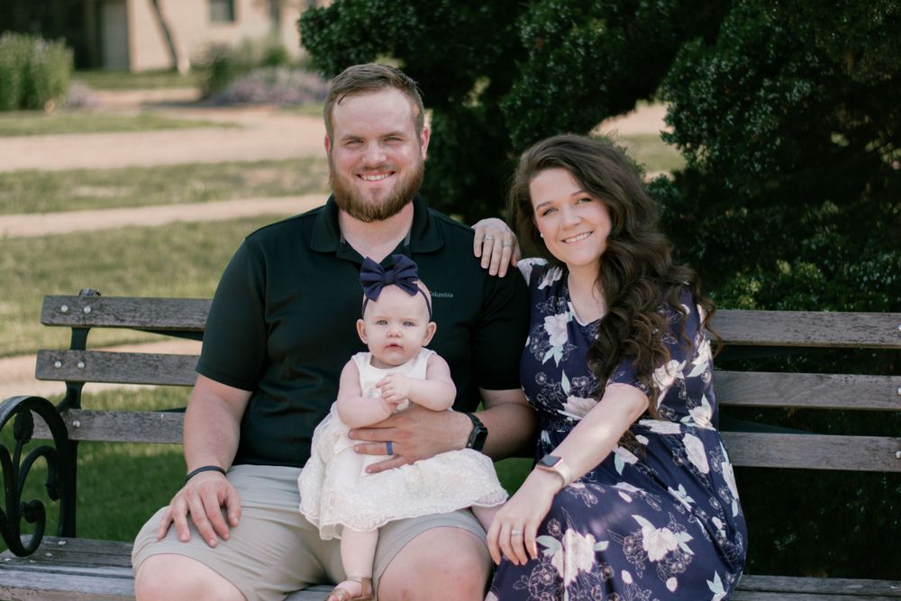 A young couple and their baby relax on a wooden bench