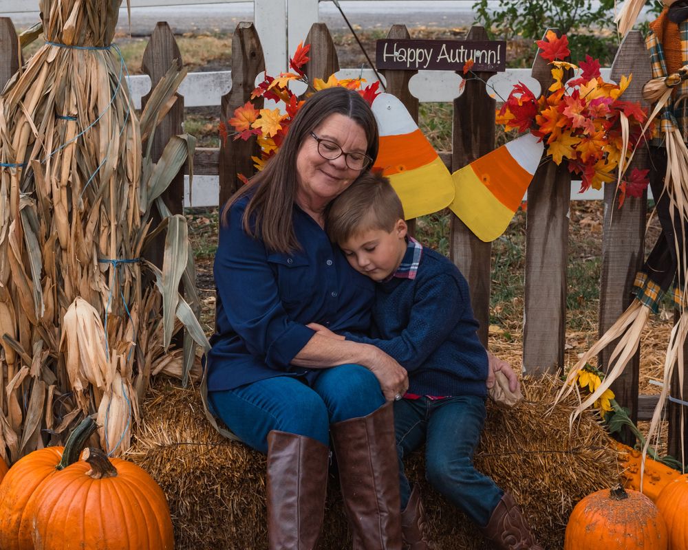A grandmother and grandson embracing at a pumpkin patch