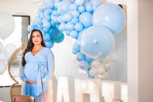 Celebration space decorated with blue balloon arch and wicker chair.