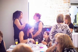 Indoor gathering with guests socializing at tables in natural light.