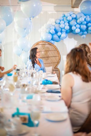 Party setup with blue balloon decorations and place settings at tables.