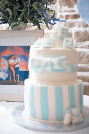 A blue and white striped cake decorated with delicate details sits on display.