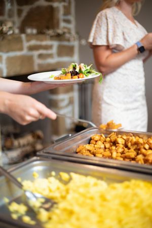 A buffet line with macaroni and cheese and roasted potatoes being served.