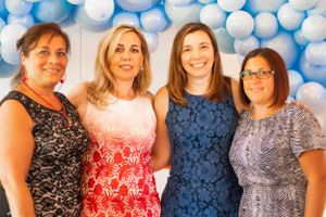 A celebration decorated with blue and white balloons features people gathered together.