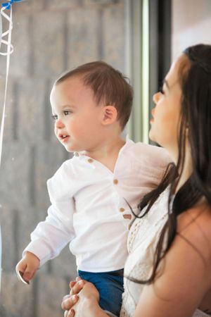 A small child in white and blue clothing reaches out during an event.