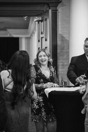 Black and white photo of guests laughing and socializing at a formal dinner party.