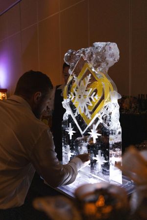 Ice sculpture artists working on an illuminated ice carving at an event.