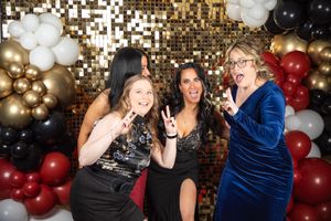 Party scene with gold sequin backdrop and festive balloon decorations.