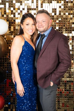 Couple posing against a gold sequined backdrop at a formal event.