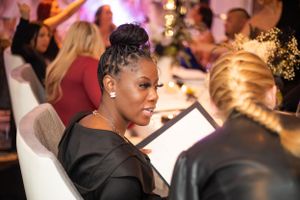 Guests enjoying an elegant dinner party with purple ambient lighting and white table settings.