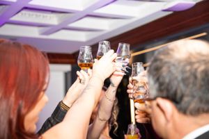 Guests raising glasses for a toast under purple ambient lighting at an event.