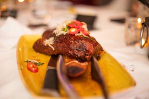 Close-up of gourmet meat dish with sauce on yellow plate in restaurant setting.