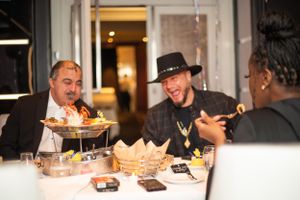 Dinner guests sharing laughs over food at elegant restaurant table.