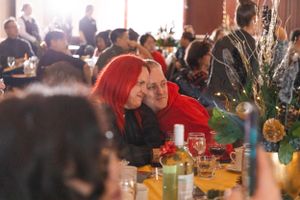 Holiday party guests seated at decorated tables with festive centerpieces.