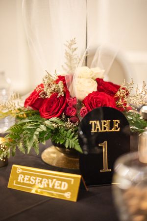 Elegant table setting with red and white roses, gold accents, and black Table 1 marker.