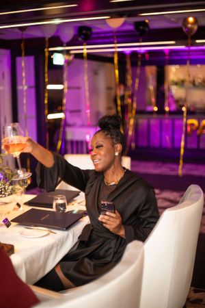 Guest raising a glass during an elegant dinner party with purple ambient lighting.