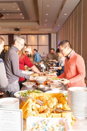 People serving themselves at holiday buffet with bread and dishes on display.