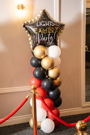 Hollywood-themed party decorations with balloon arrangements and red velvet ropes.