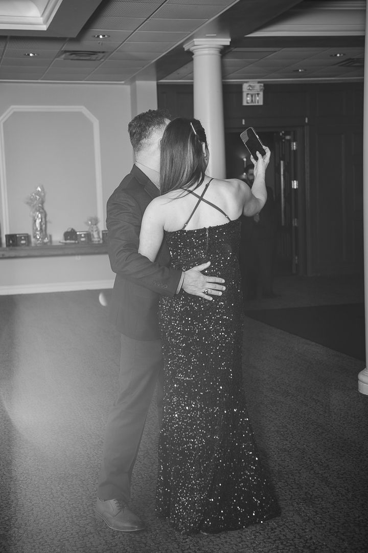 Couple embraces in black and white photo at formal event venue.
