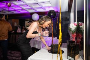 Purple-lit party venue with balloon decorations and celebratory atmosphere.