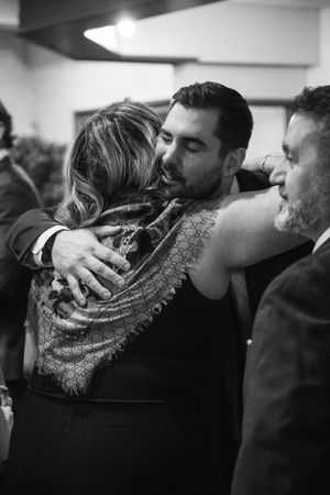 Black and white candid shot of guests embracing at an evening celebration.