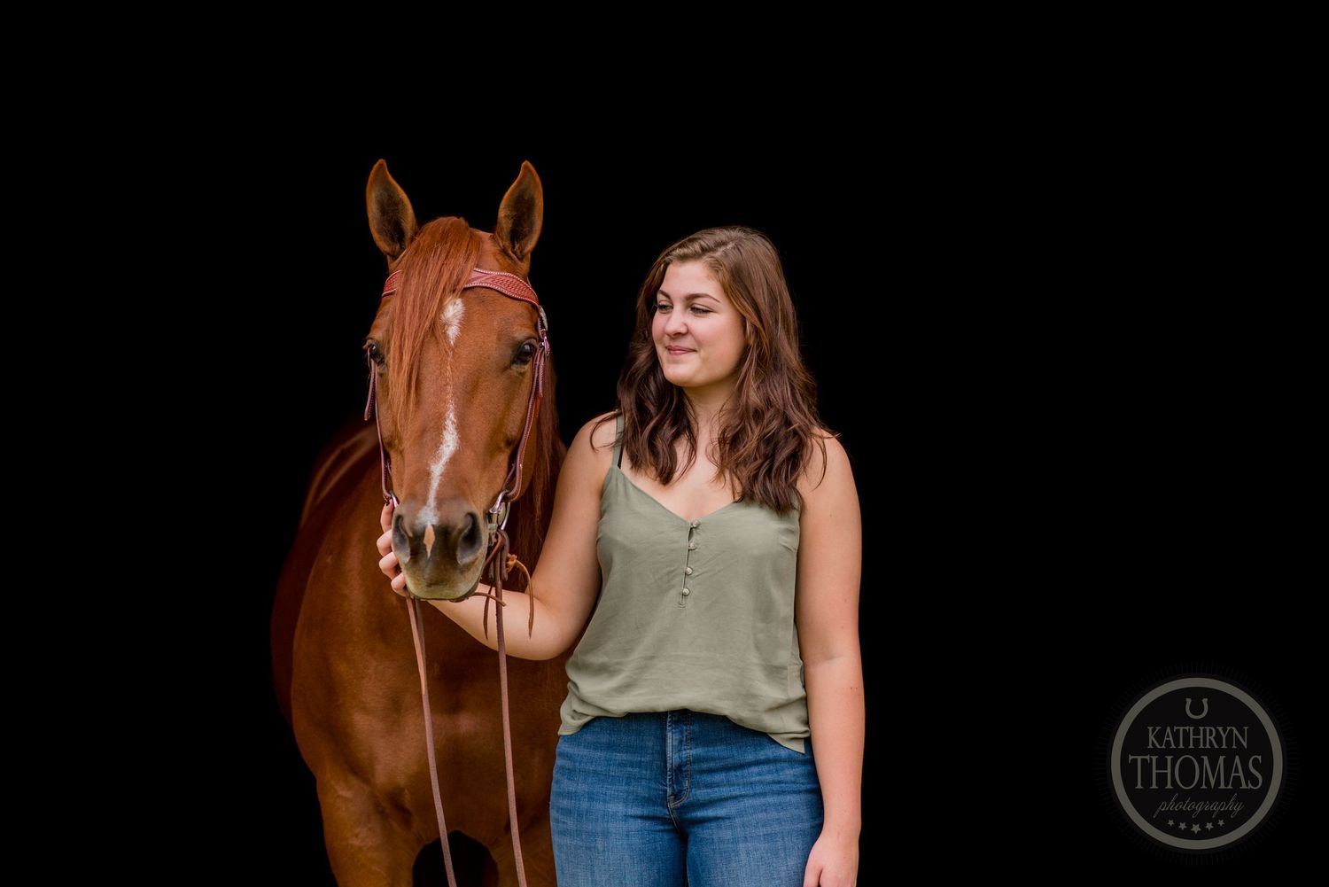 A chestnut horse and person pose together against a black background in a studio portrait.