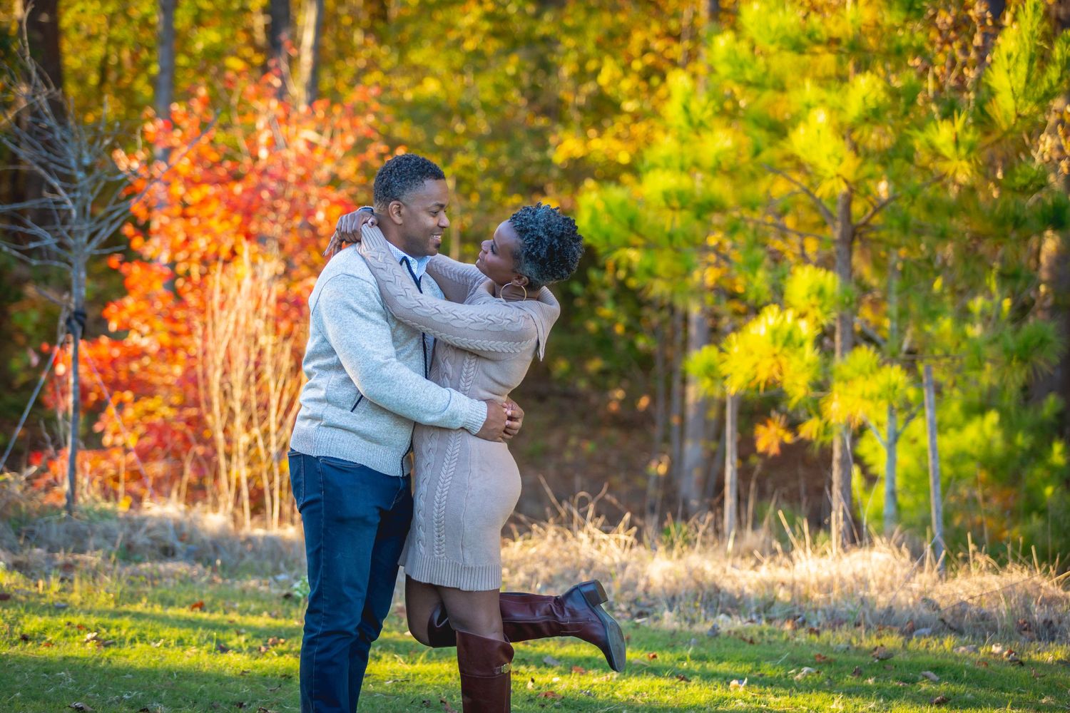 Couple embracing beneath colorful autumn leaves during an outdoor portrait session.