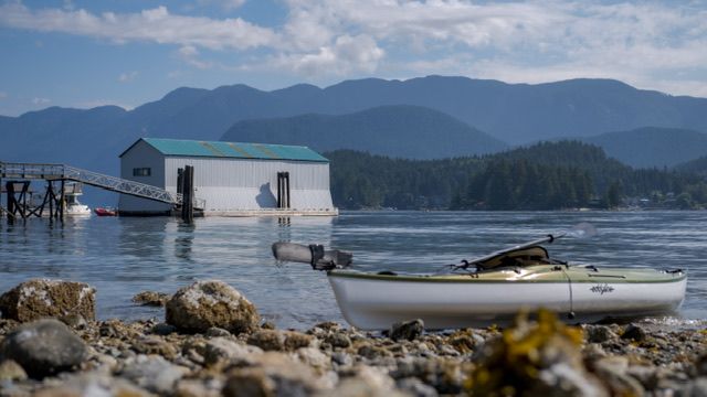 Scenic boathouse and boats on calm water with mountains in background, Deep Cove, North Vancouver