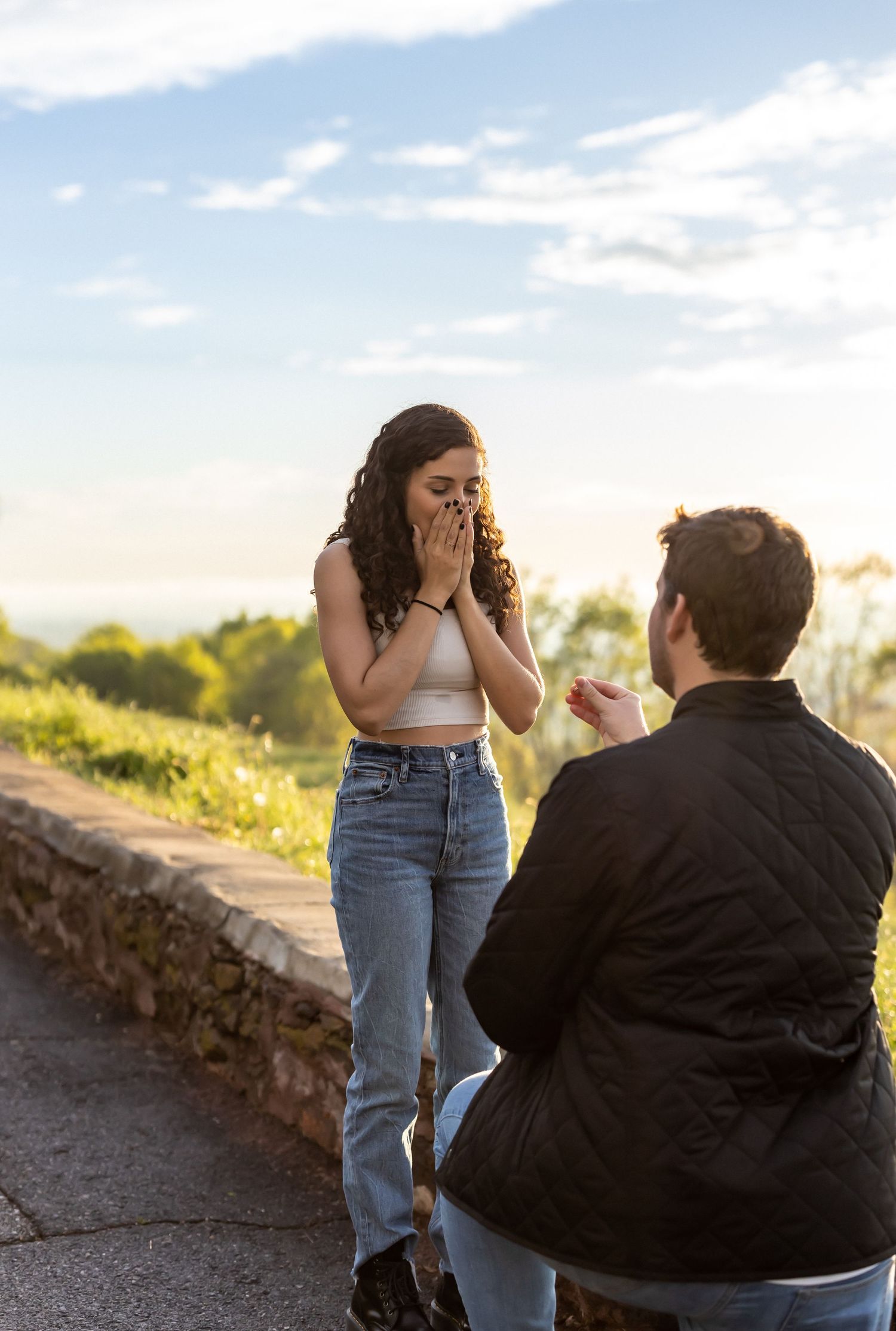Surprise proposal moment captured at sunset on stone pathway.