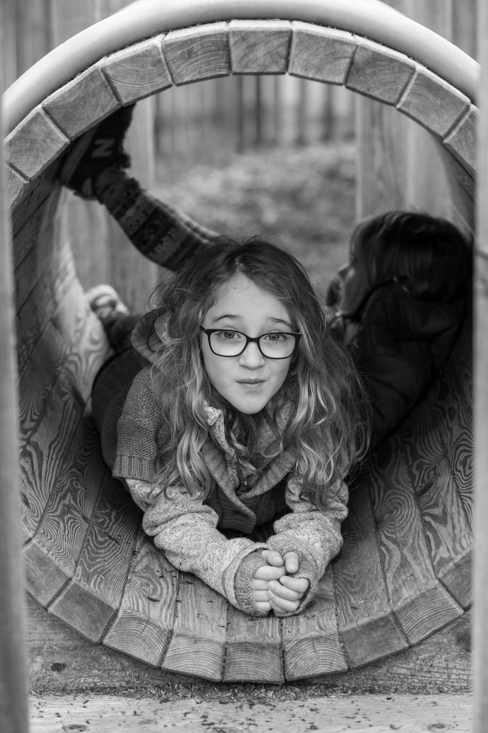 Sisters playing in playground wooden barrel, family photoshoot black and white