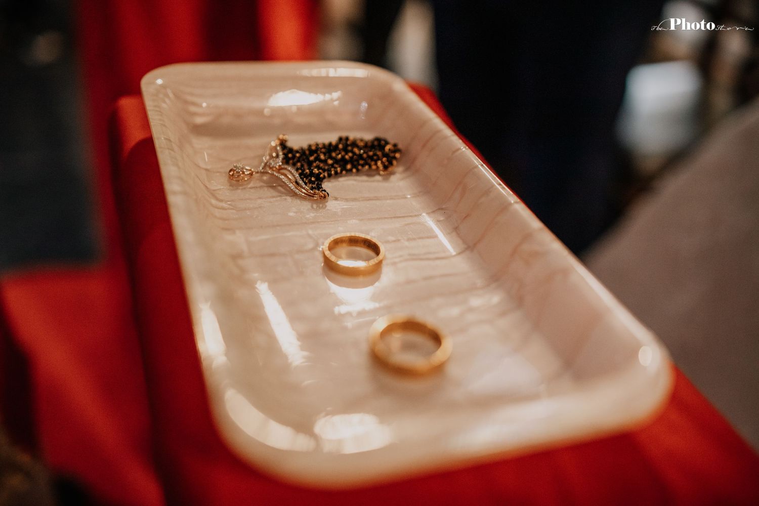 Gold wedding rings displayed on a white ceramic dish during ceremony.