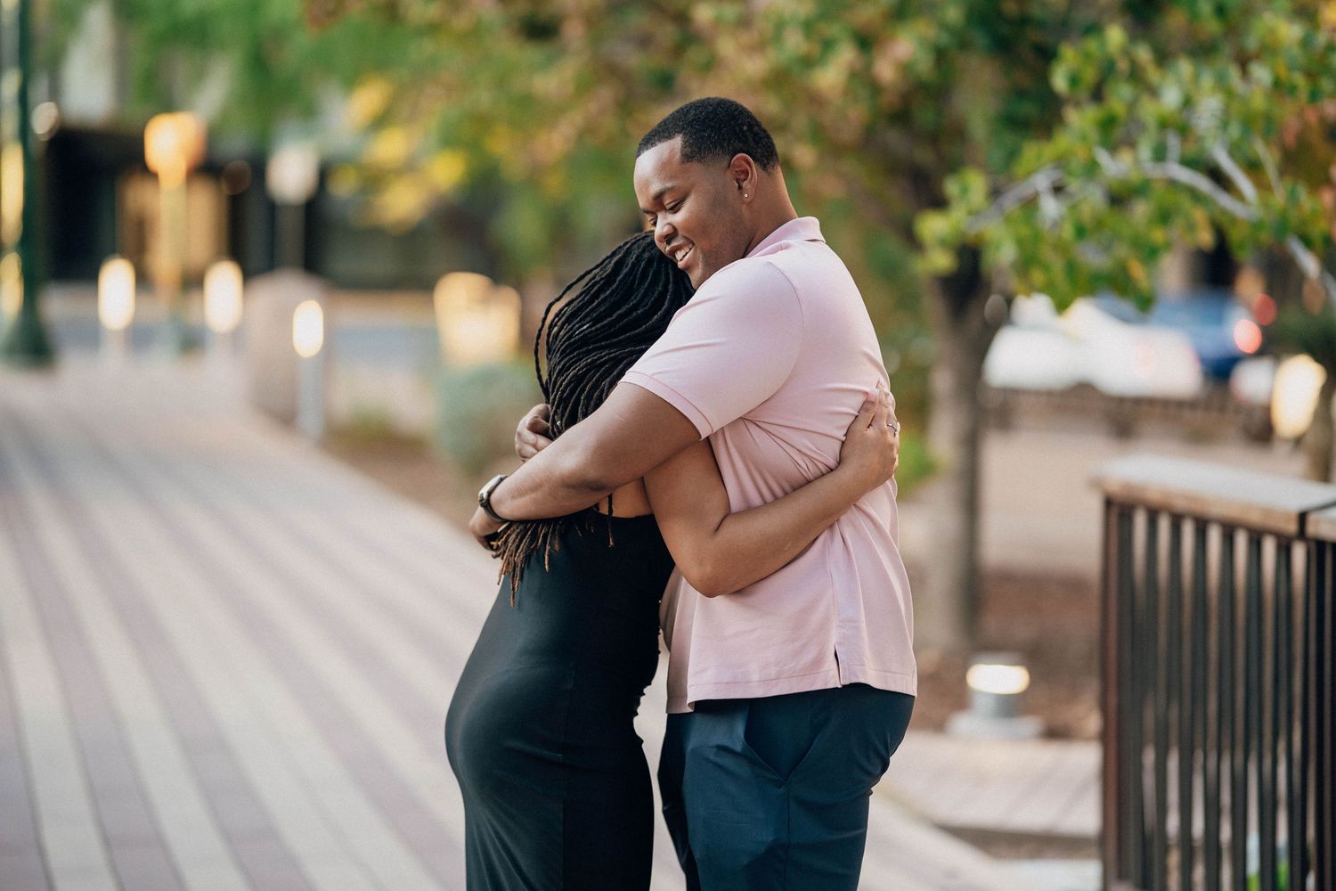A newly engaged couple hugs emotionally on a wooden walkway.