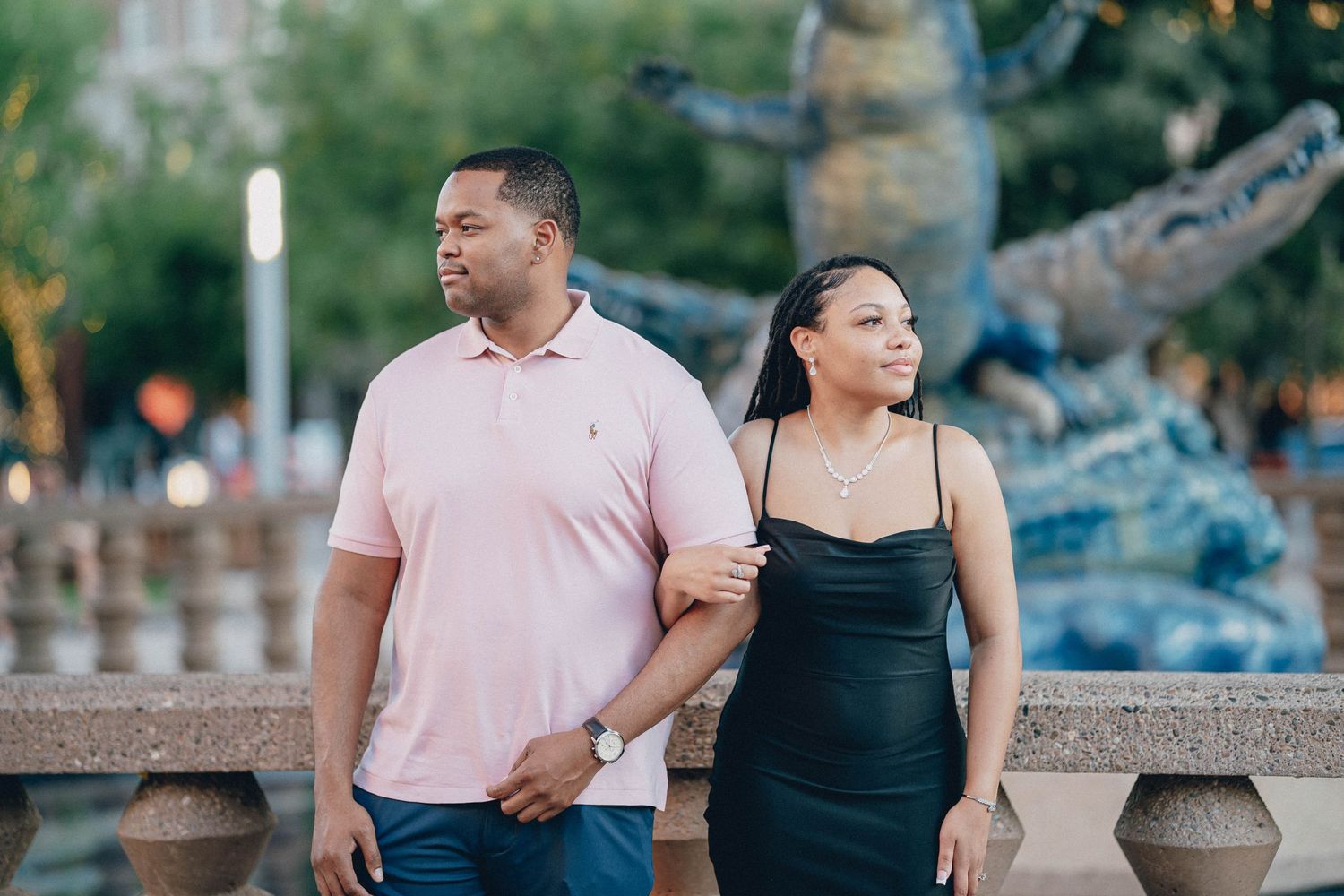 Couple poses together in outdoor portraits against blurred natural backdrop.