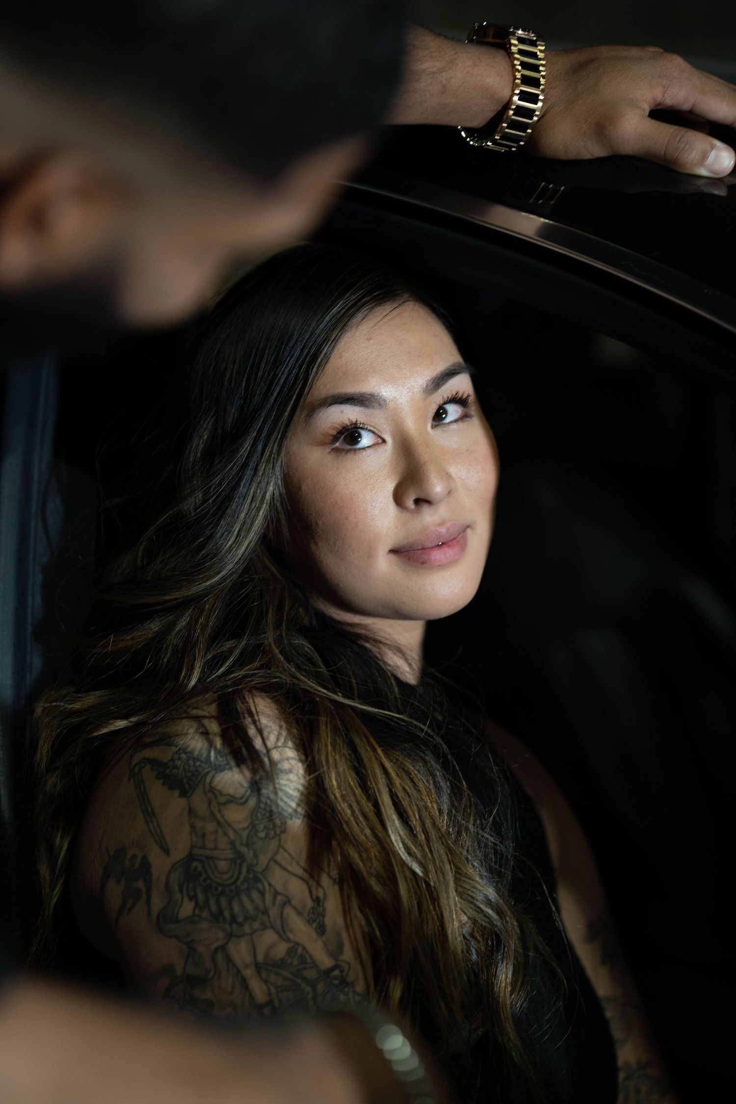 Dramatic portrait with moody lighting showing long dark hair and subtle smile.