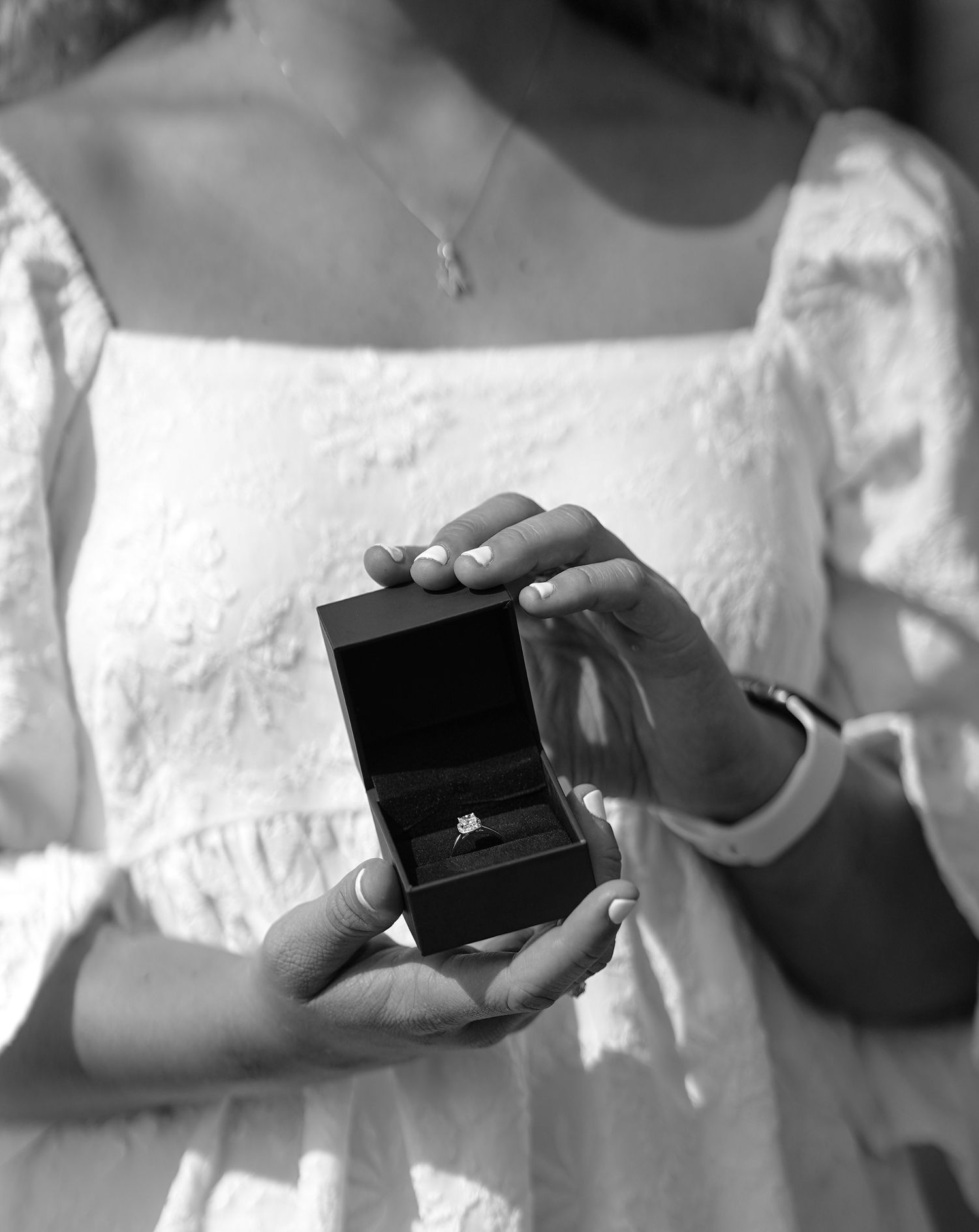 Black and white close-up shots of hands opening a small jewelry box.