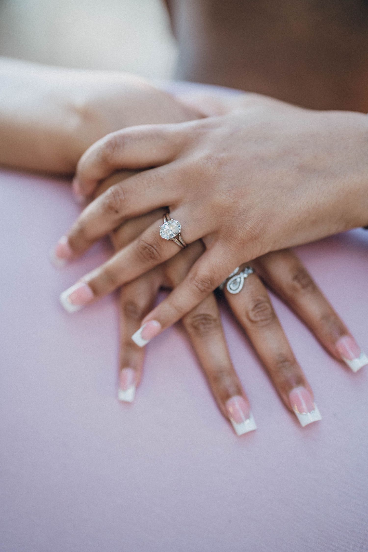Close-up of manicured hands displaying elegant engagement rings.