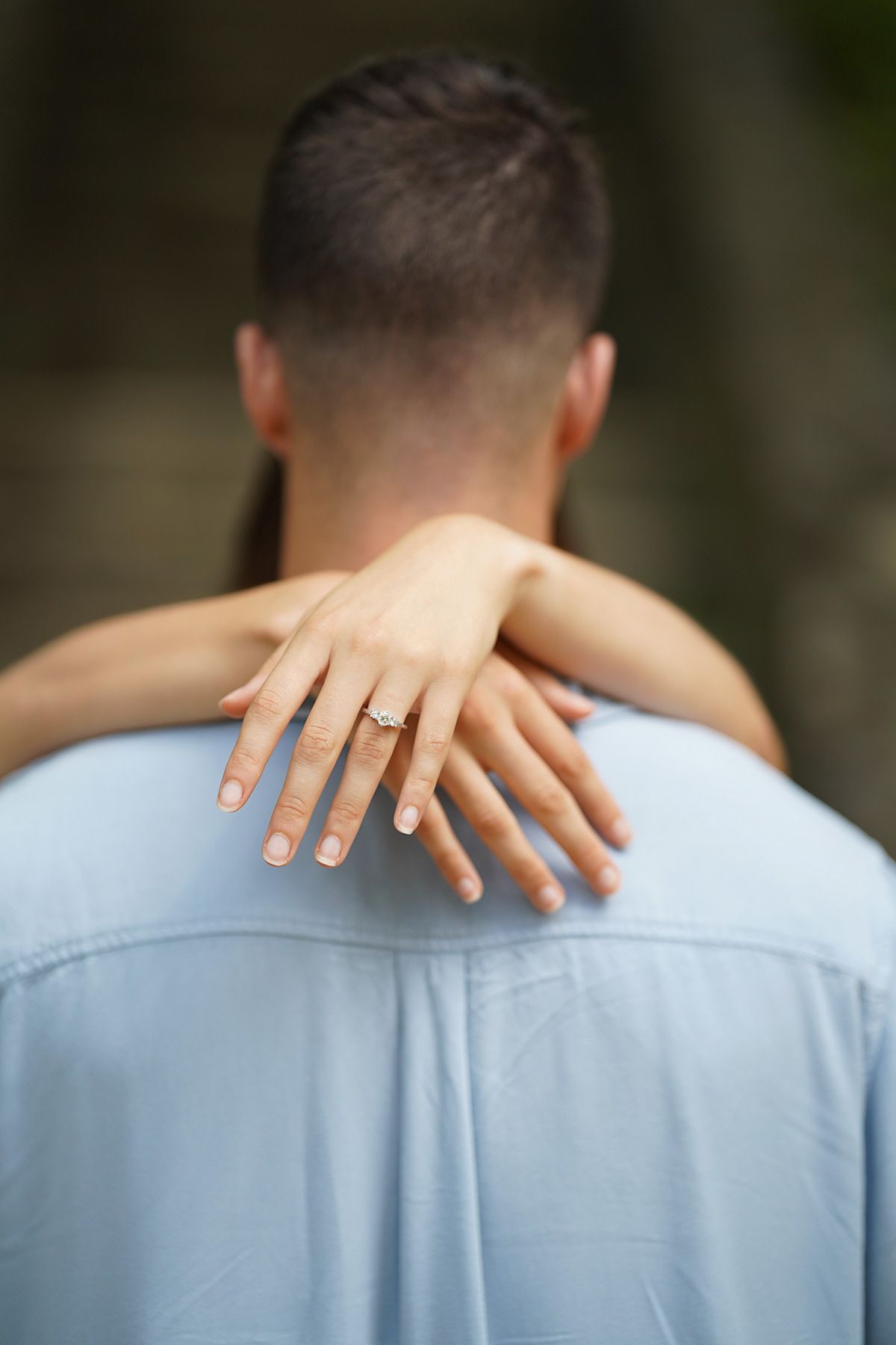 Close-up shots showing hands with engagement ring against light blue shirt.