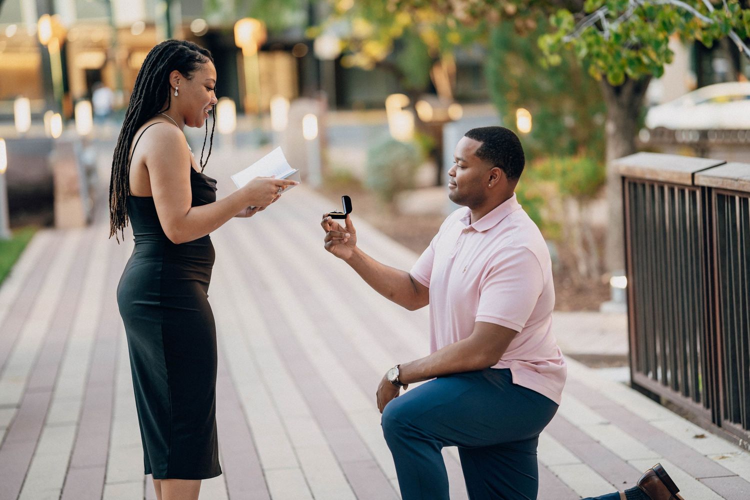 A proposal moment captured on a boardwalk during sunset.