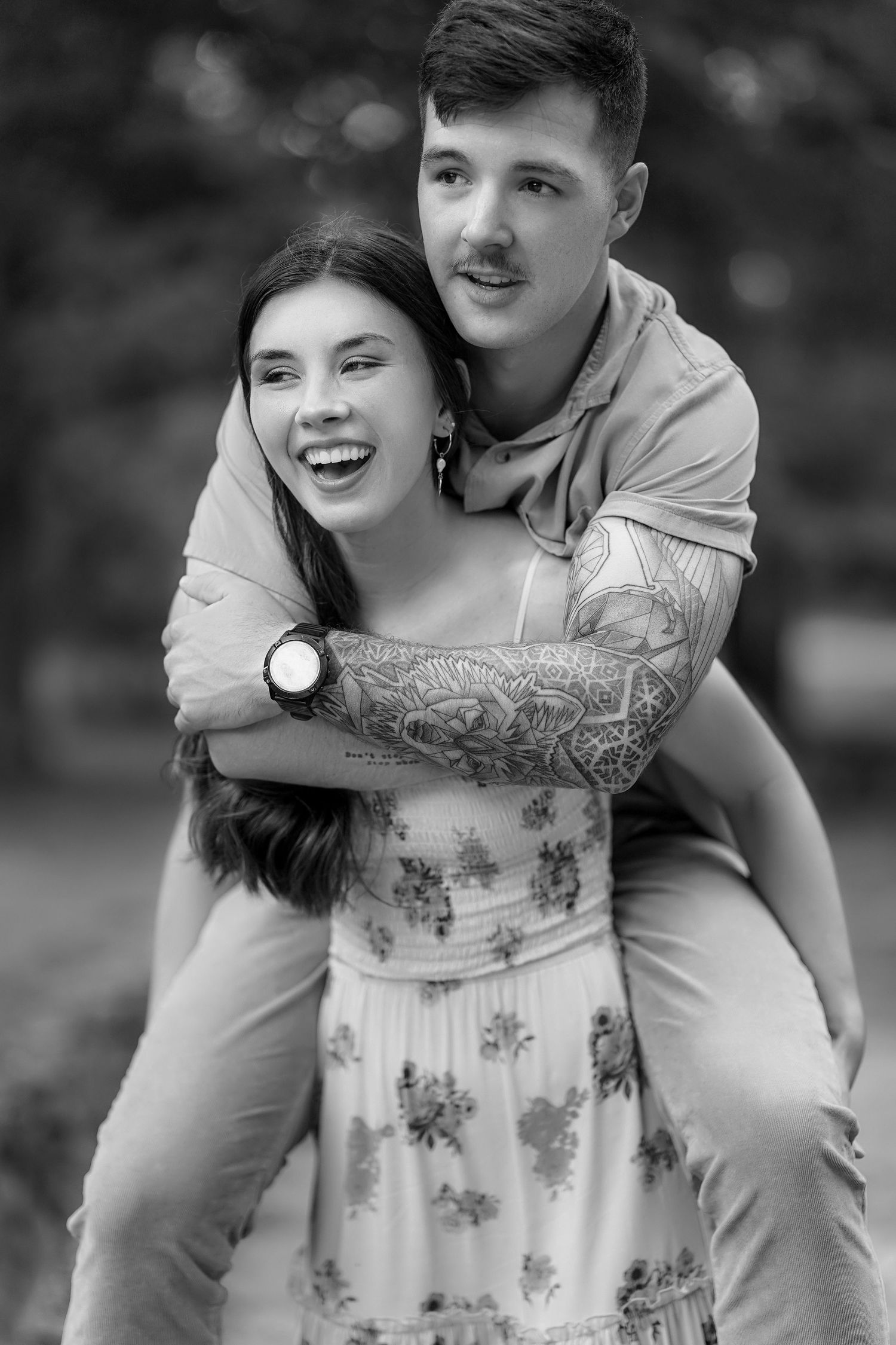 A couple embraces and laughs together in a romantic black and white photo.